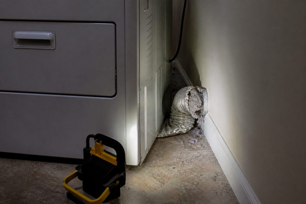 A crushed lint-packed duct behind a dryer