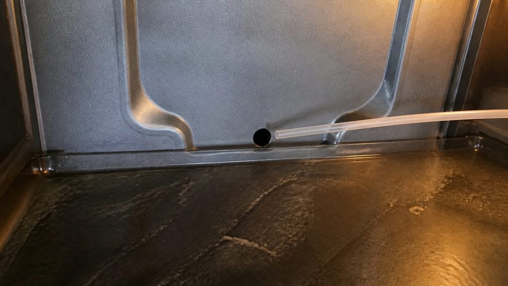 The drain hole in the liner behind the crispers